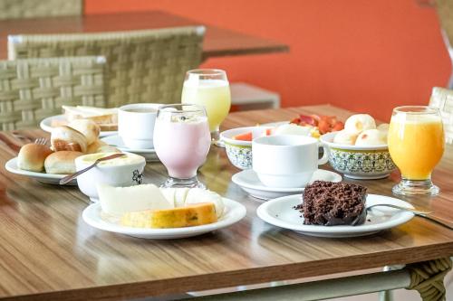 a wooden table topped with plates of food and drinks at VELINN Pousada Entre Praias in Ubatuba