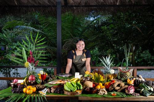 a woman standing behind a table of fruits and vegetables at Kuyana Amazon Lodge in Archidona