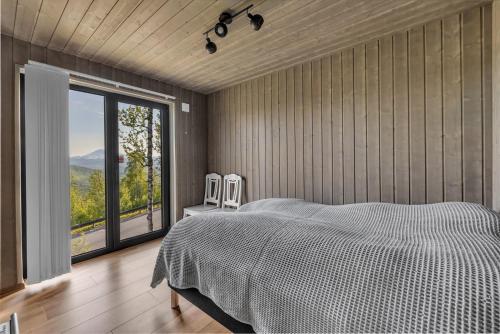 a bedroom with a bed and a large window at Målselv Fjellandsby - Cabins in Bardufoss