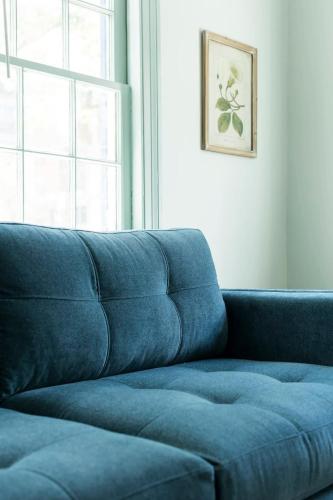 a blue couch in a living room with a window at The Ashley Carriage House Suite Includes Breakfast in Charleston