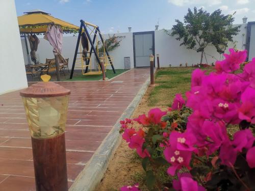 a street light next to a playground with pink flowers at Highness Villa Nizwa in Nizwa