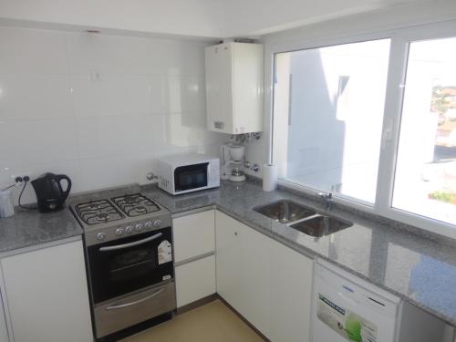 a kitchen with a stove and a sink and a window at Marco Polo Platinum Apartamento in Mar del Plata