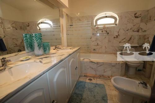 a bathroom with two sinks and a tub and a toilet at Peaceful villa with sea view close to Carvoeiro in Carvoeiro