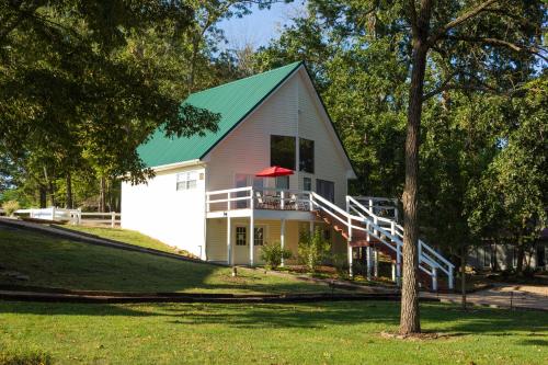 a white house with a green roof and a porch at River Ridge Inn in Norfork
