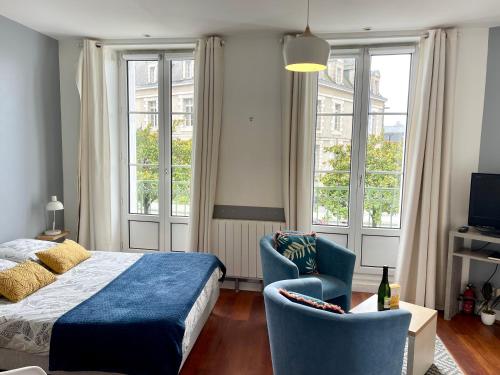 une chambre avec un lit, une chaise et des fenêtres dans l'établissement Le balcon de la place, à Dinan