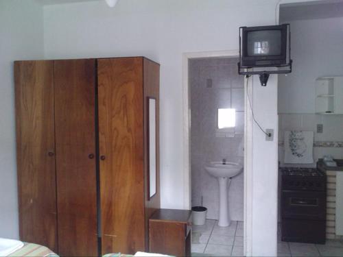 baño con armario de madera y TV. en Residencial Paraiso, en Florianópolis
