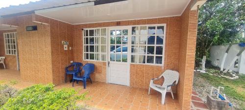 a brick house with two chairs and a door at Hotel Campestre Kosta Azul in Villavicencio