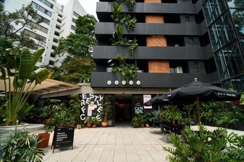 an umbrella in front of a building with plants at The Somos Central Hotel Poblado in Medellín