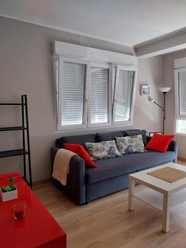 a living room with a blue couch and windows at Apartamento Salgueiro ORTIGUEIRA in Santa Marta de Ortigueira