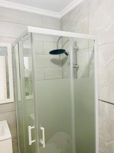 a shower with a glass door in a bathroom at Résidence Cazino Apartamentos in Praia