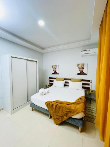 a bedroom with a large white bed with yellow curtains at Résidence Cazino Apartamentos in Praia