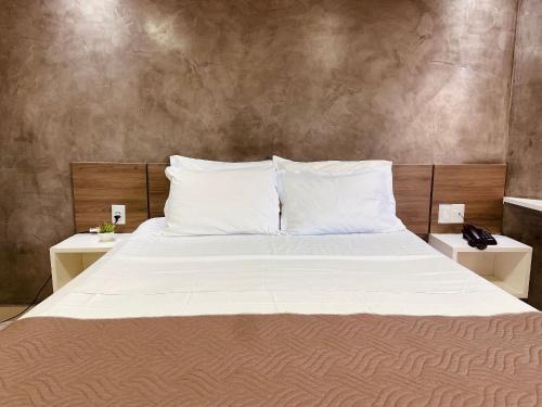 uma cama grande com lençóis brancos e travesseiros em Aptos super confortáveis no Gold Flat by Apartamentos Jampa em João Pessoa