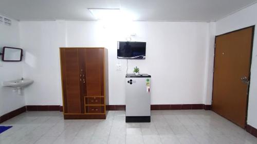 a room with a refrigerator and a tv on a wall at Apartment near Central Festival Hatyai in Hat Yai