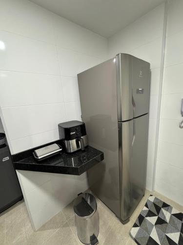a kitchen with a stainless steel refrigerator and a counter at Praia dos Anjos Residence Club in Arraial do Cabo