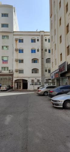 a parking lot with cars parked in front of a building at Muscat Galaxy Hostel in Muscat