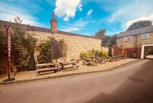 a group of benches and umbrellas next to a brick building at Longs Hotel & Inn in Woburn