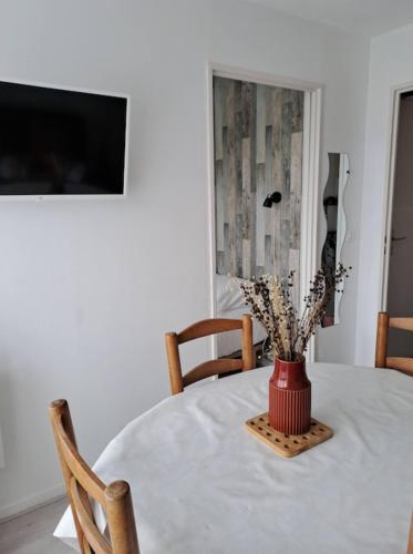 une table avec un vase de fleurs dessus dans l'établissement L'Evasion, F2 proche mer et commerce, parking & wifi, à Villers-sur-Mer