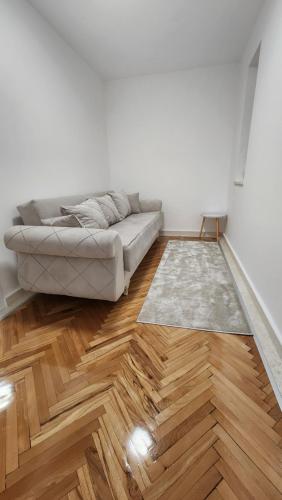 a living room with a couch and wooden floors at City Center Relax Podgorica in Podgorica