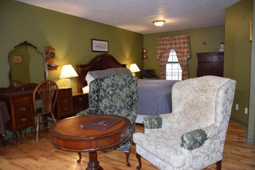 a bedroom with a bed and a chair and a table at Auberge Wild Rose Inn in Moncton