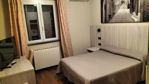 a small bedroom with a bed and a window at Hotel La Meridiana in Urbino
