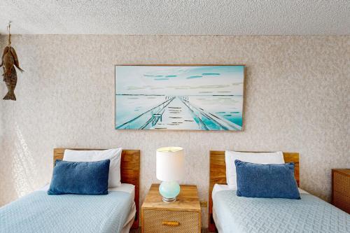 a bedroom with two beds and a painting on the wall at Tradewinds Plaza 906 in Honolulu