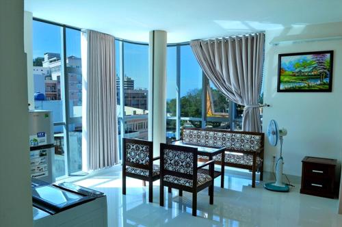 ein Wohnzimmer mit einem Tisch, Stühlen und Fenstern in der Unterkunft Lotus Apartment Hotel in Vũng Tàu