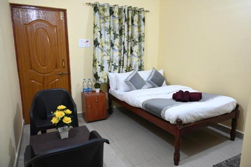 a bedroom with a bed and a chair and a window at Margaritas Residency in Benaulim