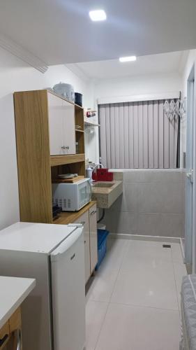 a small kitchen with white cabinets and a microwave at ** SUITE PRIVATIVA PRAIA DO FORTE CABO FRIO ** in Cabo Frio