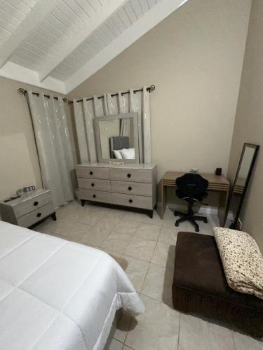 a bedroom with a bed and a chair and a mirror at CIsland Experience in Montego Bay