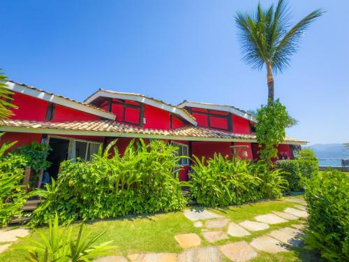 a red house with a palm tree in front of it at Pousada Vila das Velas in Ilhabela
