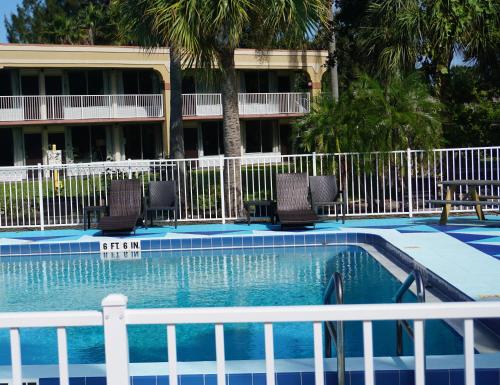 a swimming pool in a resort with chairs and a fence at ISLAND HOTEL of Space Coast in Merritt Island
