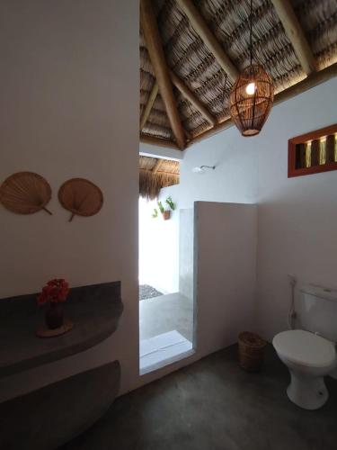 a bathroom with a toilet and two umbrellas on the wall at Casa da Lagoa - Pousada Icaraí Kite Village in Amontada