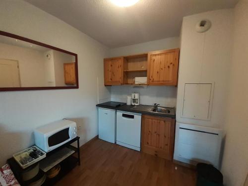 - une petite cuisine avec des placards en bois et un four micro-ondes dans l'établissement Chalet Florence - 2 Pièces pour 4 Personnes MAE-6501, à Modane