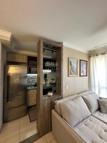 a living room with a couch and a kitchen at apartamento climatizado, 3 quartos c suíte garden in Cuiabá