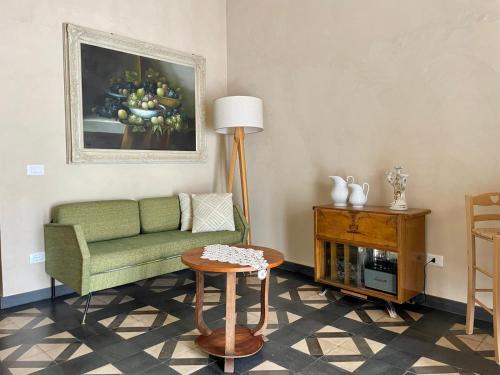 a living room with a green couch and a painting at Maison Yolo - Slow Living Sicily in Agrigento