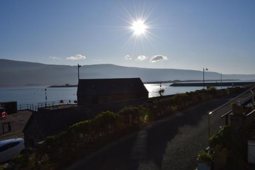 a sun is shining over a body of water at Wynnstay Apartment, Harbour and Mountain Views in Barmouth