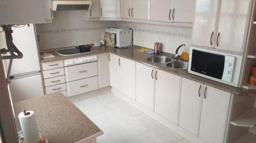 a small kitchen with white cabinets and a sink at Habitacion Privada Familiar Toledo in Toledo