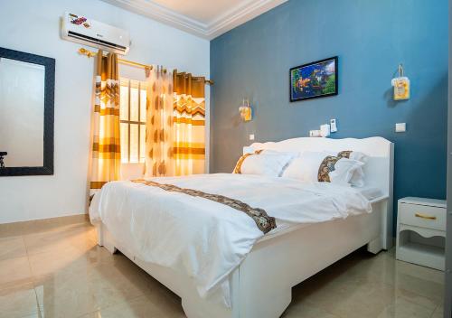 Un dormitorio con una cama blanca y paredes azules. en magnifique appartement, de deux balcons, très spacieux, en Baguida