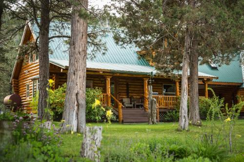 a log cabin with a porch and trees at Lonesome Duck Ranch in Chiloquin
