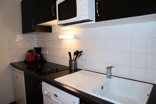 un comptoir de cuisine avec un évier et un micro-ondes dans l'établissement Residence La Combe D Or - Appartement en résidence de standing MAE-6304, aux Orres