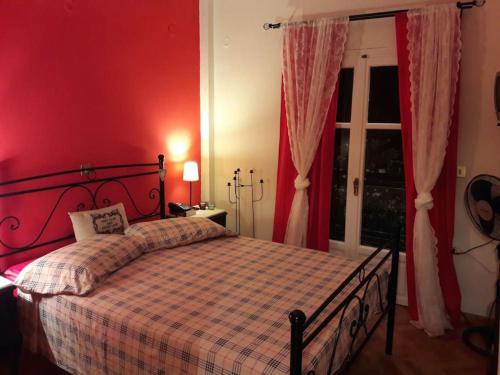 a bedroom with a bed with red walls and a window at Diktynna Villa in Palekastron