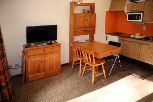 une cuisine avec une table en bois et une télévision sur une armoire dans l'établissement Résidence Le Pouzenc - Studio calme pieds de pistes MAE-6471, aux Orres