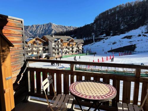 d'une table et d'une chaise sur un balcon avec une piste de ski. dans l'établissement Résidence Parc Des Airelles - APPARTEMENT PARC DES AIRELLES 110 MAE-7291, aux Orres