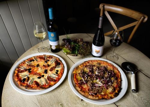 two pizzas on a table with bottles of wine at Queen's Head Askham in Penrith