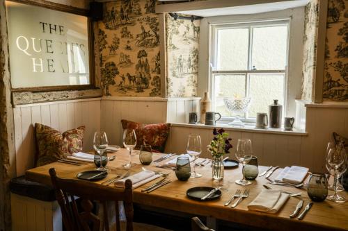 a wooden table with wine glasses and napkins at Queen's Head Askham in Penrith