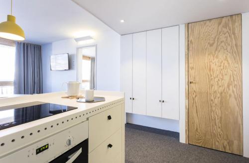 - une cuisine avec des placards blancs et une porte en bois dans l'établissement Résidence Thuria - Spacieux 3 pièces 7/8 personnes MAE-4644, à Arc 1800