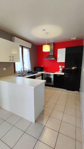 une cuisine avec un comptoir blanc et des murs rouges dans l'établissement Maison spacieuse à Morsang sur Orge, idéale pour 8, à Morsang-sur-Orge