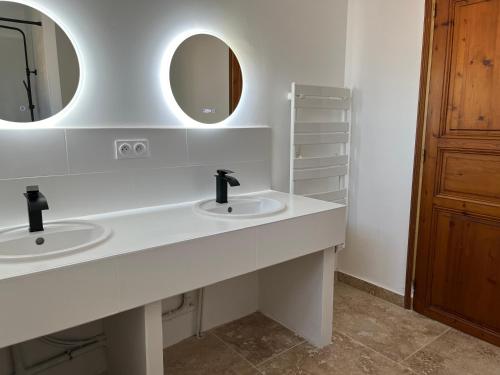 une salle de bain blanche avec deux lavabos et un miroir dans l'établissement Maison 10 couchages, 5km des plages, 12km de Montpellier, à Pérols
