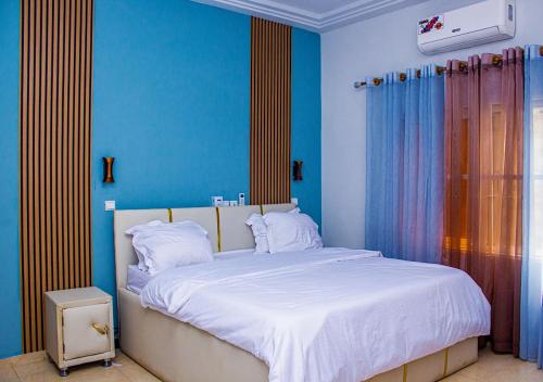a bedroom with a large white bed with blue walls at Très beau logement à Baguida in Lomé