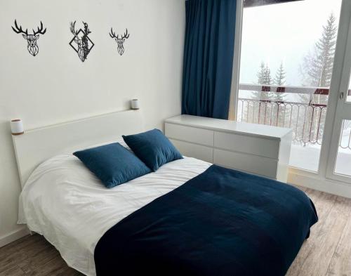 une chambre avec un lit avec des oreillers bleus et une fenêtre dans l'établissement Résidence Varet 2 - Appartement rénové 3 pièces 7 personnes MAE-4774, à Arc 2000